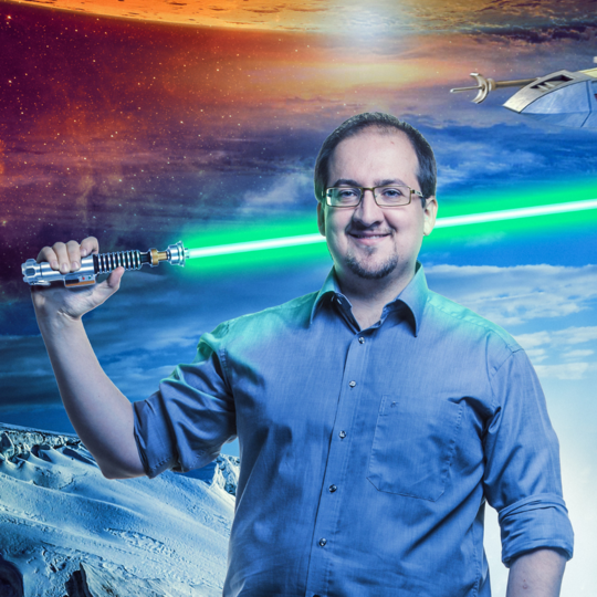 Person mit Brille und blauem Hemd hält ein leuchtendes grüne